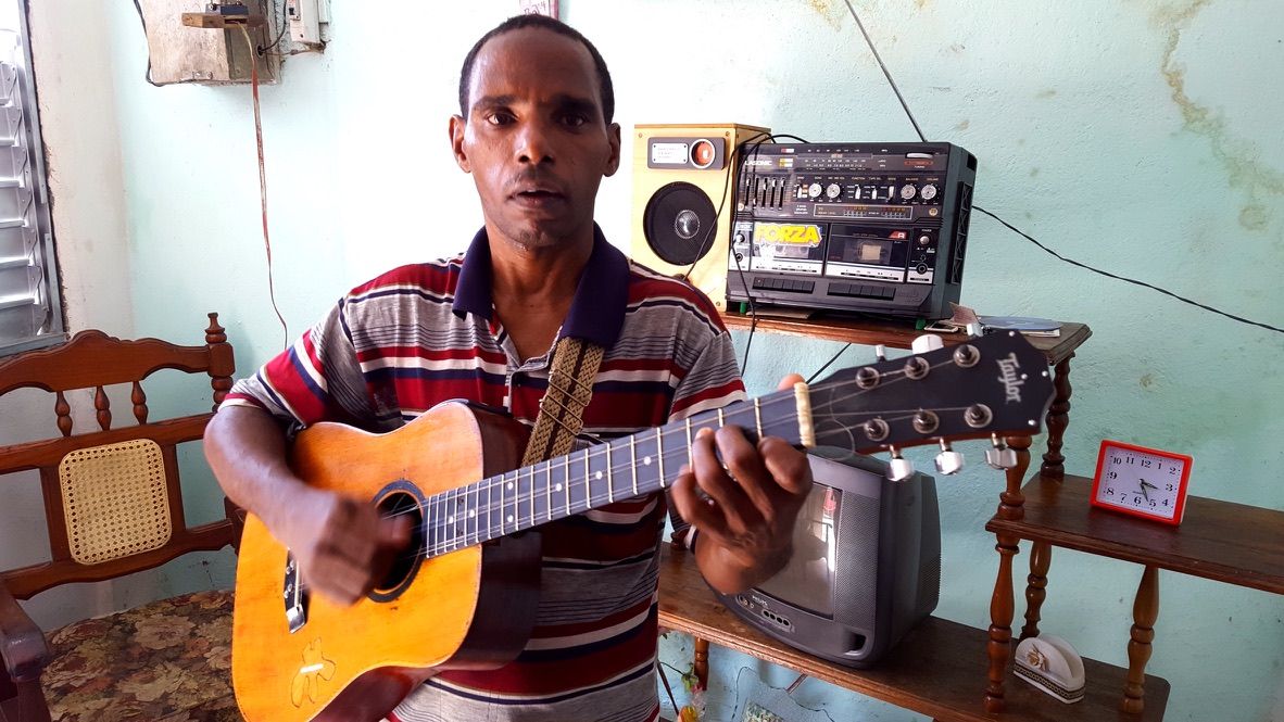 A Cuban guitarist playing in a room during one of Michael’s visits