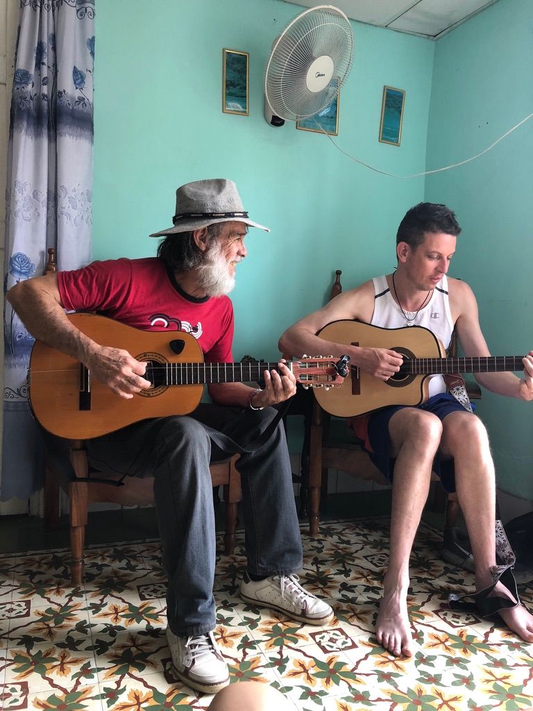 Michael Terkowski playing guitar with a musician during a visit to Cuba