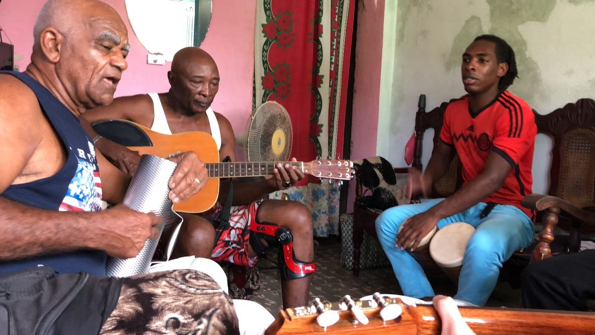 Musicians playing guitar, güiro and percussion together in Cuba